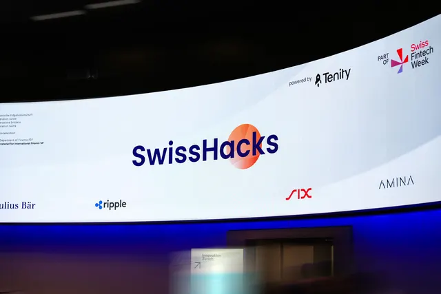 The curved LED stage wall showing the SwissHacks logo with the partner logos beside it.